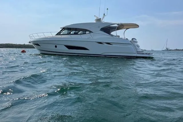 Happy Ours Yacht Photos Pics 2019 Riviera 5400 Sport Yacht cruising on open water under clear skies.