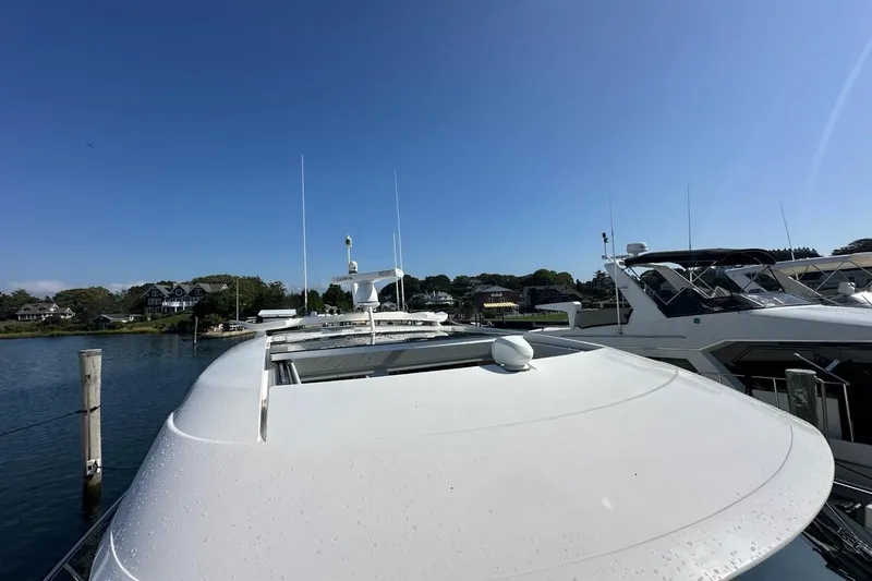Happy Ours Yacht Photos Pics 2019 Riviera 5400 Sport Yacht docked in a scenic marina under clear blue skies.