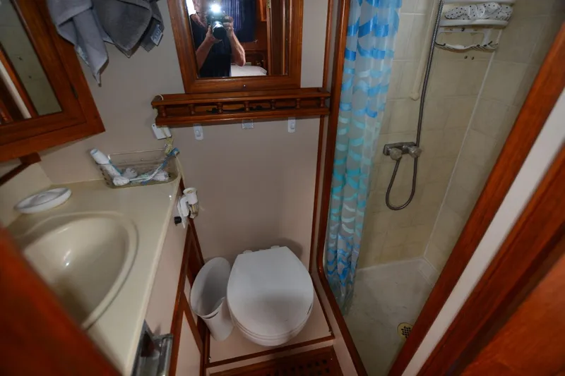 Pau Hana Yacht Photos Pics Compact bathroom in a 1998 Monk Trawler, featuring a shower, toilet, and sink.