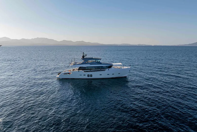Firefly Yacht Photos Pics 2025 Sanlorenzo SX76 yacht cruising on open sea with scenic mountain backdrop.