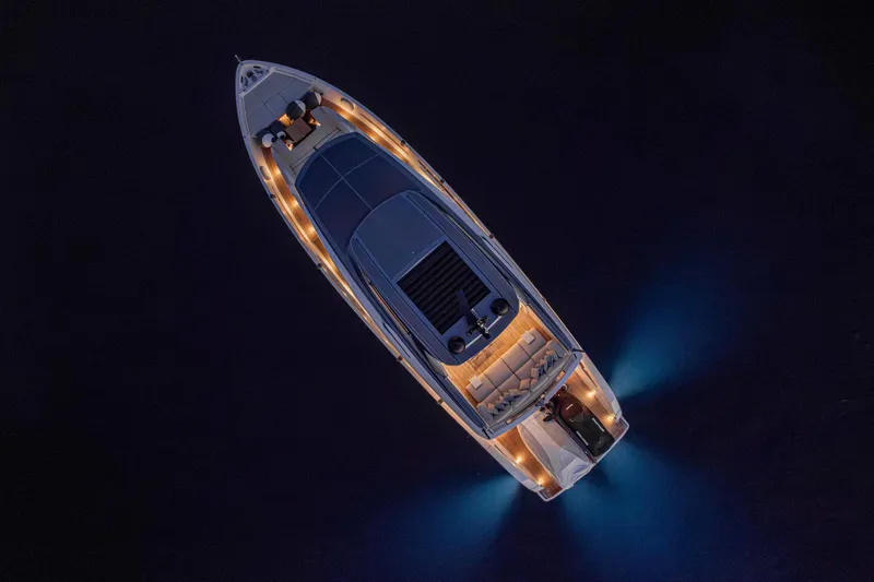 Firefly Yacht Photos Pics Aerial view of 2025 Sanlorenzo SX76 yacht illuminated at night on dark water.