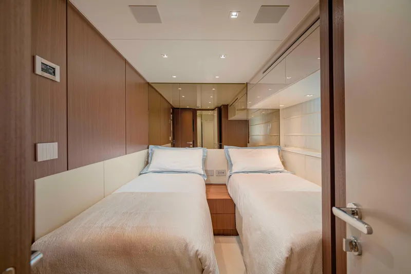 Firefly Yacht Photos Pics Luxurious twin bedroom in 2025 Sanlorenzo SX76 yacht, featuring modern wood paneling and elegant lighting.