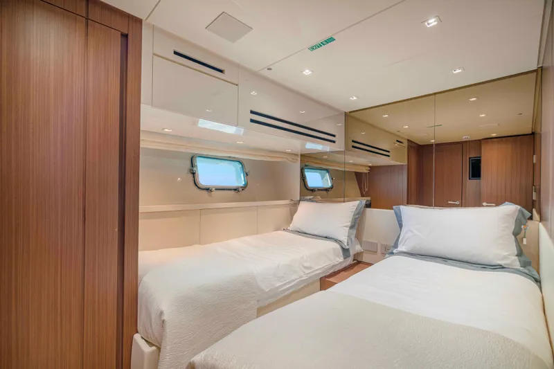 Firefly Yacht Photos Pics Luxurious twin bedroom on 2025 Sanlorenzo SX76 yacht, featuring modern wood paneling and porthole windows.