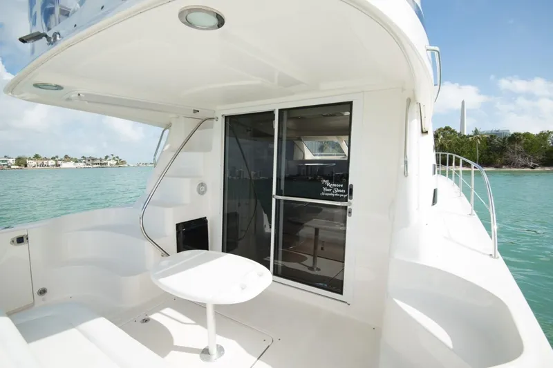 Jody Yacht Photos Pics 2006 Sea Ray 44 Sedan Bridge yacht deck with sliding glass door, overlooking serene waters.
