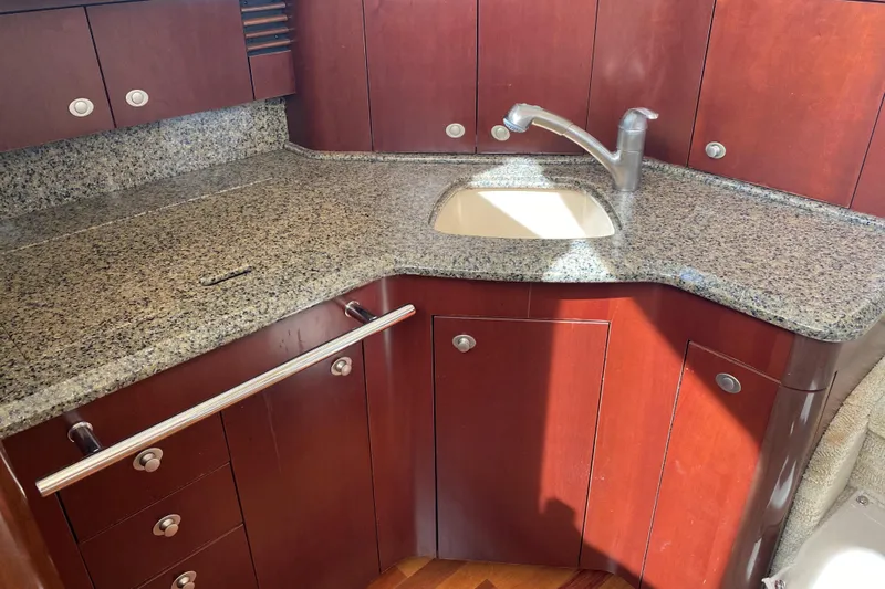 Jody Yacht Photos Pics Luxurious 2006 Sea Ray 44 Sedan Bridge kitchen with granite countertop and wooden cabinetry.