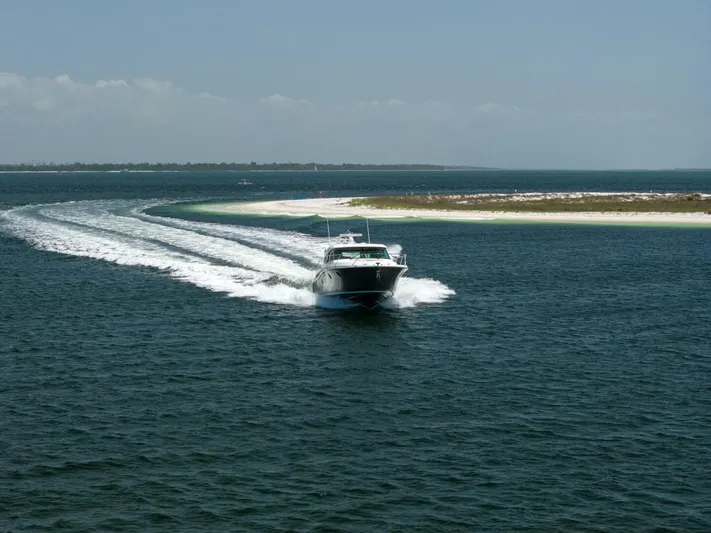 Silver Lining Yacht Photos Pics 2015 Tiara Yachts 44 Coupe cruising on open water near a sandy shoreline.