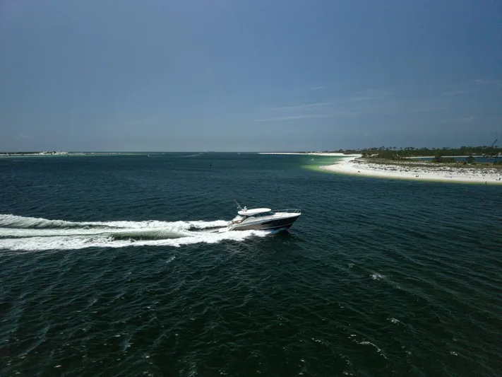 Silver Lining Yacht Photos Pics 2015 Tiara Yachts 44 Coupe cruising on open water near a sandy shoreline.