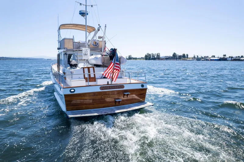 Celebration Yacht Photos Pics 1988 Grand Banks 42 Classic yacht cruising on open water, rear view with American flag.