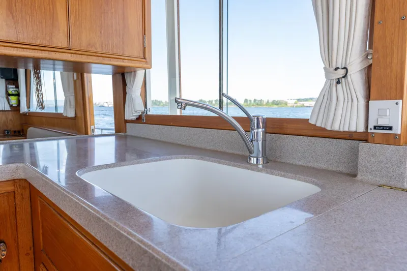 Celebration Yacht Photos Pics Galley sink in 1988 Grand Banks 42 Classic yacht with wooden cabinetry and window view.