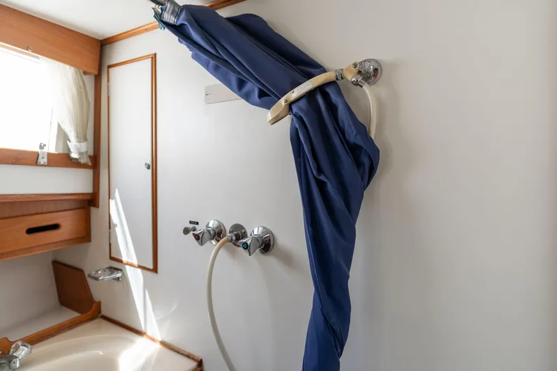 Celebration Yacht Photos Pics Shower area in 1988 Grand Banks 42 Classic yacht with blue curtain and wooden accents.