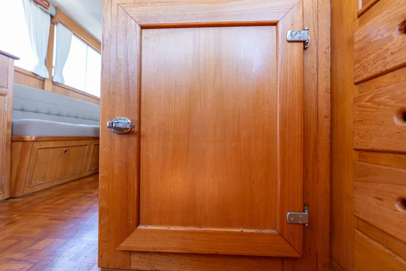 Celebration Yacht Photos Pics Wooden interior of 1988 Grand Banks 42 Classic yacht, featuring a cabinet door and seating area.