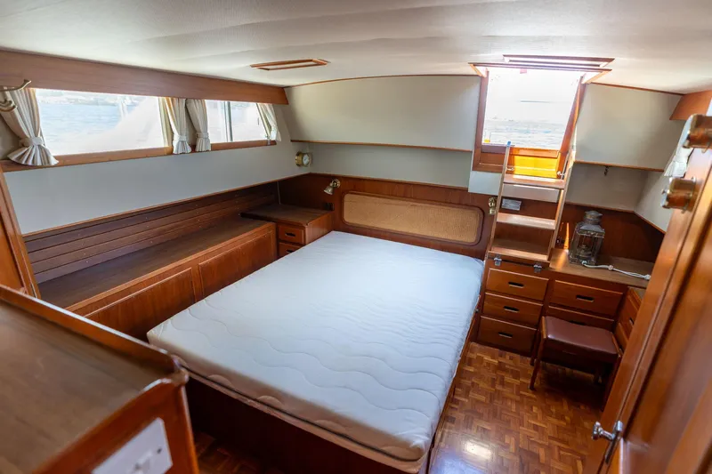 Celebration Yacht Photos Pics Interior of 1988 Grand Banks 42 Classic yacht, featuring a cozy bedroom with wooden furnishings.