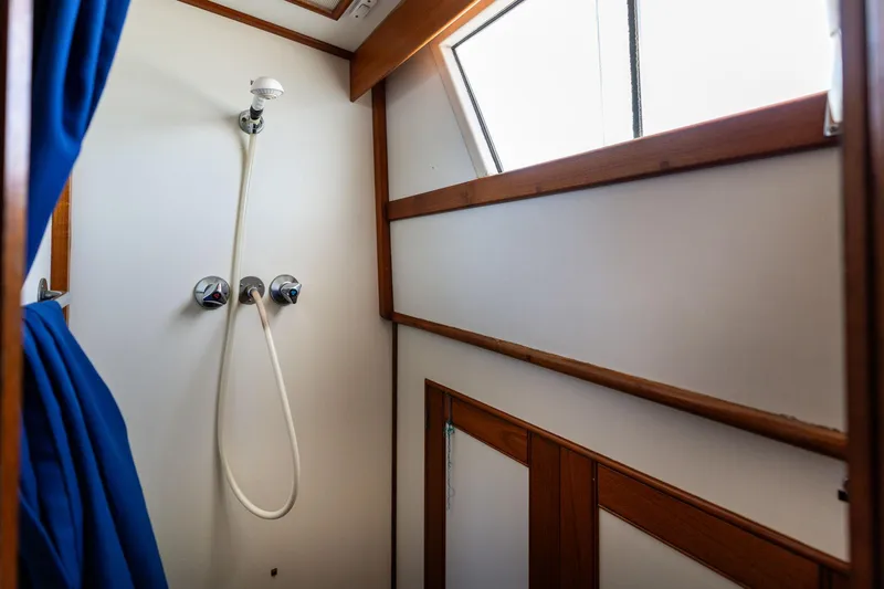 Celebration Yacht Photos Pics Shower area inside 1988 Grand Banks 42 Classic boat with wooden trim and blue curtain.