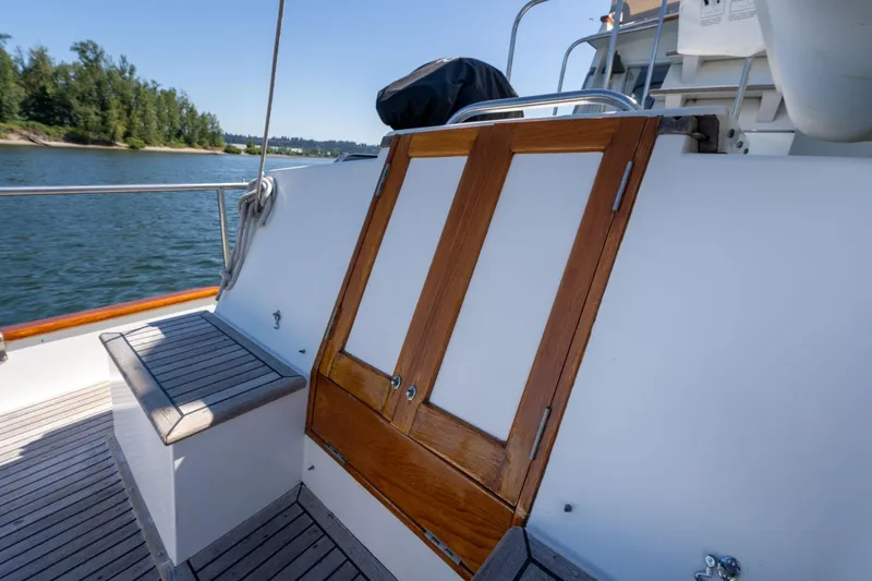Celebration Yacht Photos Pics 1988 Grand Banks 42 Classic yacht deck with wooden doors and seating, near scenic waterway.