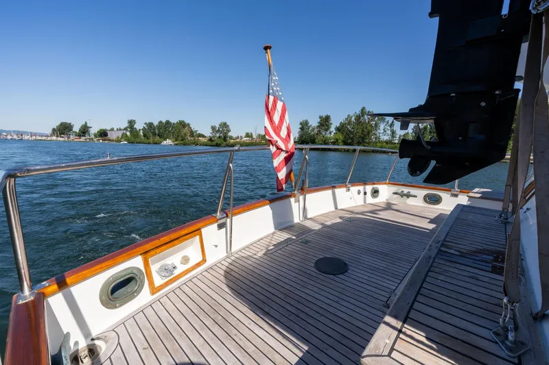 Celebration Yacht Photos Pics 1988 Grand Banks 42 Classic yacht deck with American flag, cruising on a serene waterway.