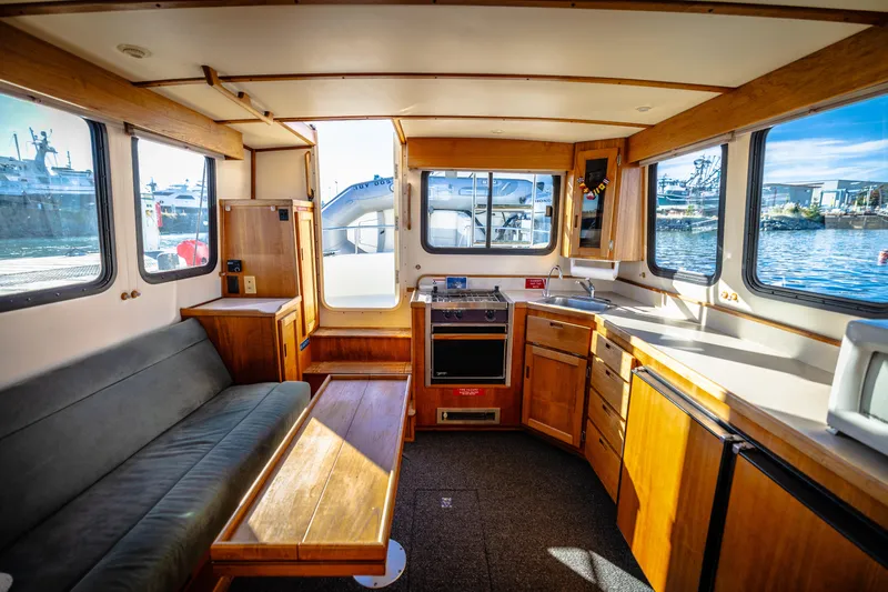 Old Bro Yacht Photos Pics Interior of 2001 Nordic Tug 32 with kitchen and seating area, featuring wood cabinetry.