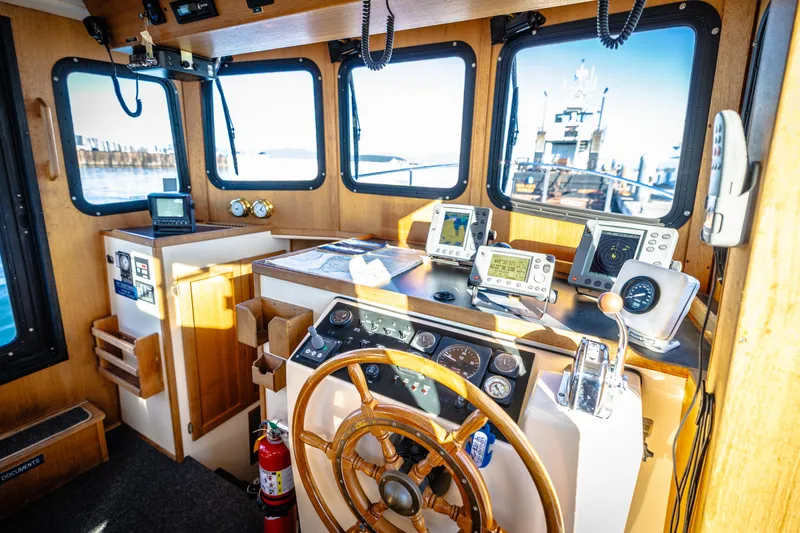Old Bro Yacht Photos Pics Cabin interior of 2001 Nordic Tug 32 with navigation equipment and wooden steering wheel.
