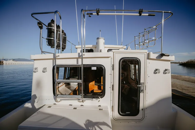 Old Bro Yacht Photos Pics 2001 Nordic Tug 32 boat docked, rear view with clear sky and water background.