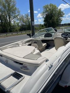 2004 Sea Ray 185 Sport boat with beige interior, parked near a road under a clear sky.