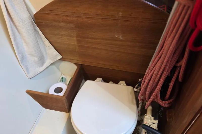 Blue Star Yacht Photos Pics Compact marine toilet area in 2018 Tofinou 12 sailboat, featuring wooden paneling and nautical ropes.