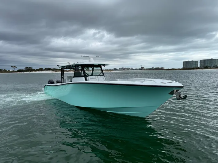  Yacht Photos Pics 2023 Yellowfin 42 Offshore boat cruising on a cloudy day near the shoreline.