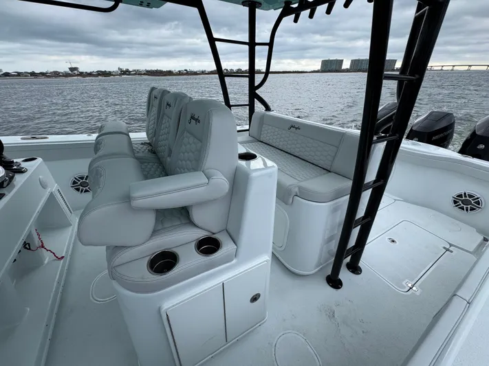  Yacht Photos Pics 2023 Yellowfin 42 Offshore boat interior with cushioned seating and cup holders on a calm water backdrop.