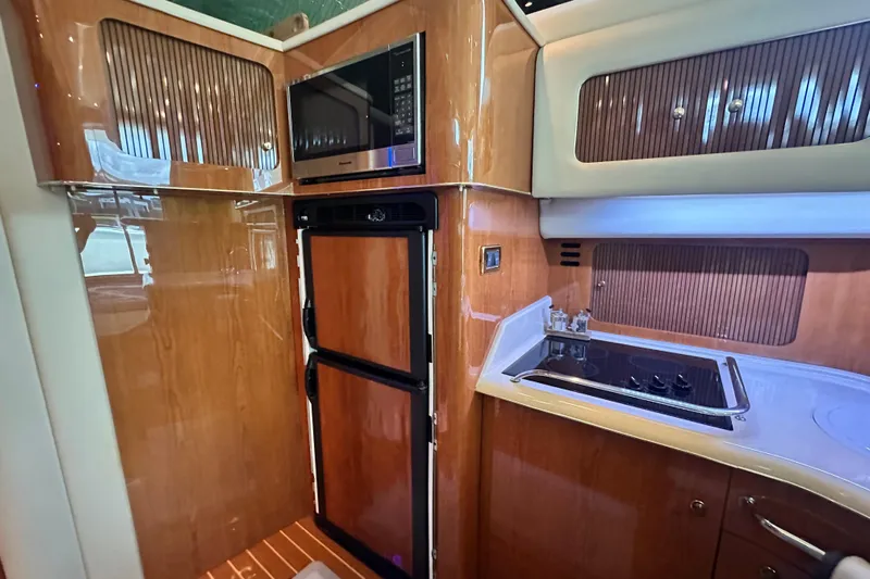 August Moon Yacht Photos Pics 2001 Sea Ray 400 Sedan Bridge kitchen with wood cabinetry, stove, and microwave.