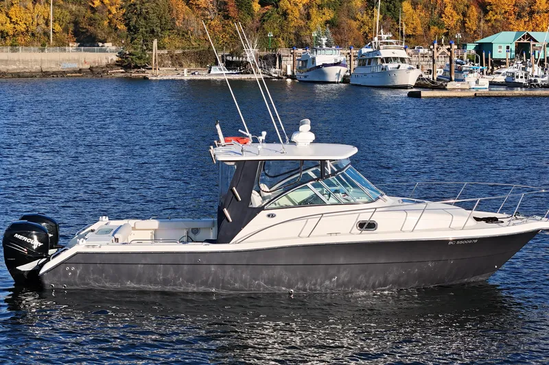  Yacht Photos Pics 2006 Pursuit 3070 Offshore boat on calm water near marina with autumn foliage.