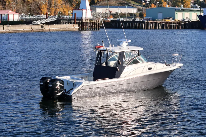 Yacht Photos Pics 2006 Pursuit 3070 Offshore boat on calm water near a marina.