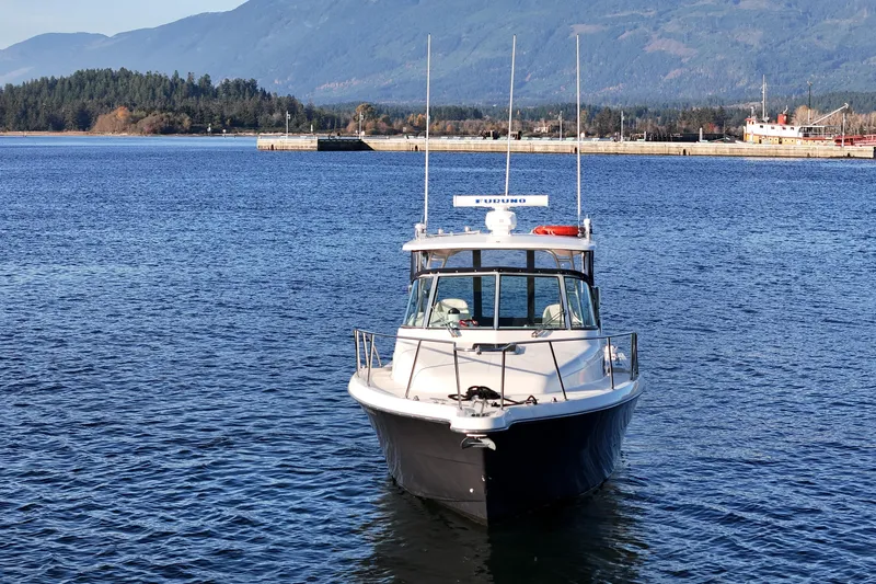  Yacht Photos Pics 2006 Pursuit 3070 Offshore boat on calm water with mountainous backdrop.