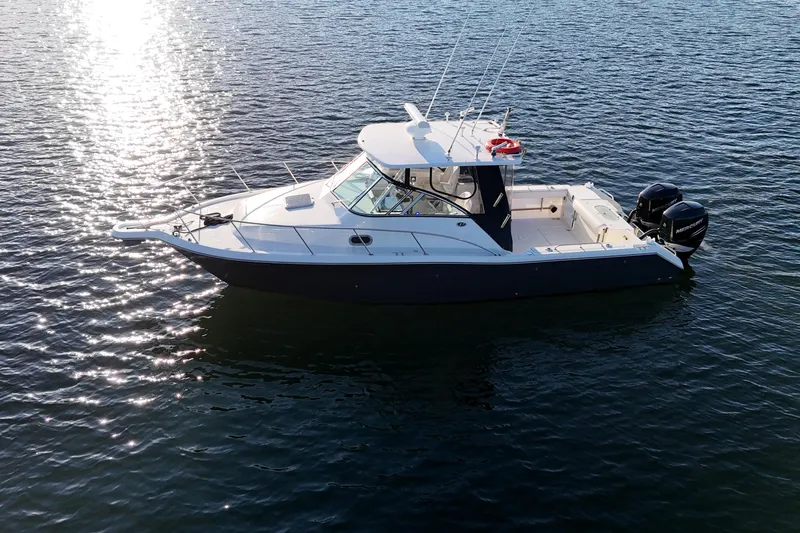  Yacht Photos Pics 2006 Pursuit 3070 Offshore boat on calm water, reflecting sunlight.