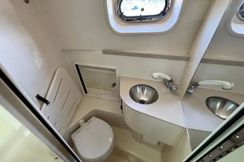  Yacht Photos Pics 2006 Pursuit 3070 Offshore boat bathroom with sink, toilet, and porthole window.