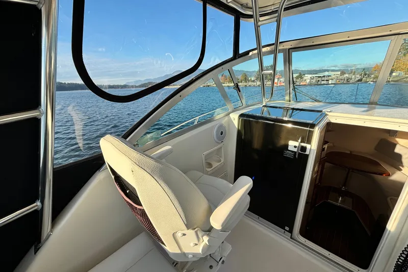  Yacht Photos Pics 2006 Pursuit 3070 Offshore boat interior with helm seat, cabin, and scenic water view.