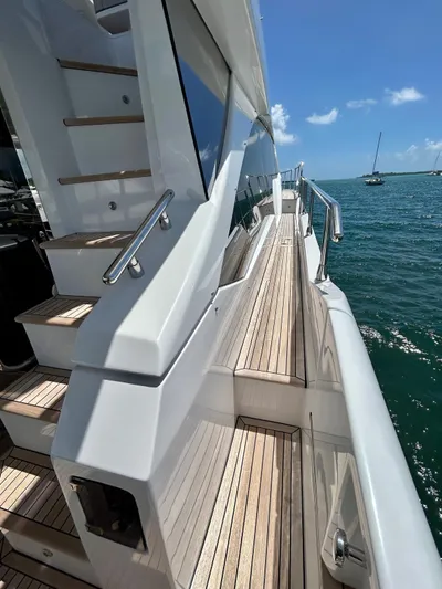  Yacht Photos Pics 2023 Azimut Fly 60 yacht with sleek design and wooden deck, cruising on a sunny day.