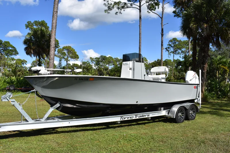  Yacht Photos Pics 2025 Latitude Tournament Boats 25 on trailer, surrounded by trees and blue sky.