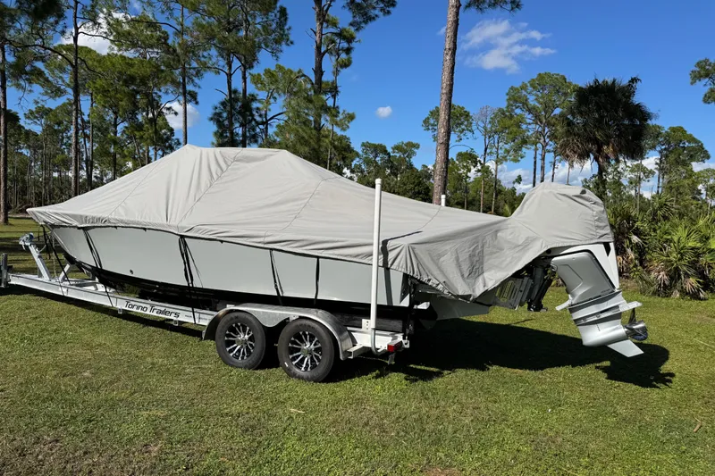 Yacht Photos Pics Covered 2025 Latitude Tournament Boats 25 on trailer, parked on grass with trees in background.