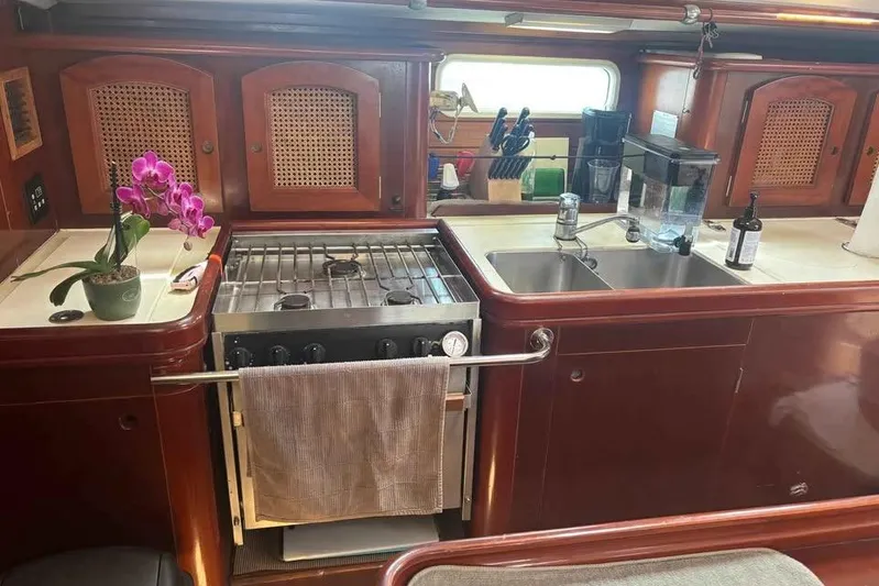 Must Love Dogs Yacht Photos Pics Galley kitchen in a 1996 Beneteau 50 yacht with stove, sink, and orchid.