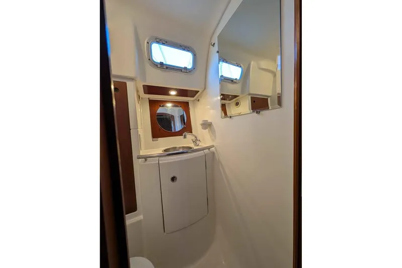 Must Love Dogs Yacht Photos Pics Bathroom interior of 1996 Beneteau 50 yacht, featuring sink, mirror, and porthole window.
