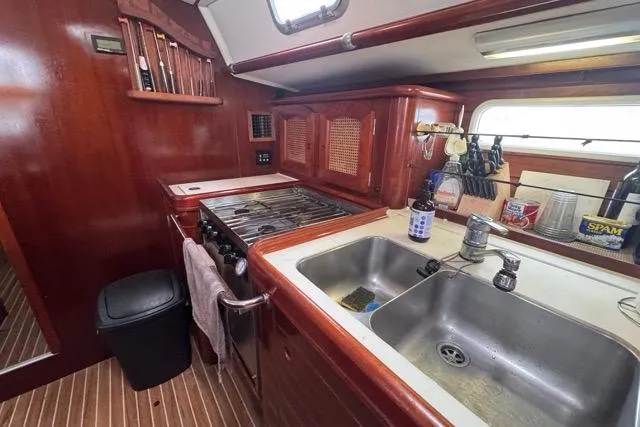 Must Love Dogs Yacht Photos Pics Galley kitchen in 1996 Beneteau 50 yacht with wooden cabinetry and dual sink.