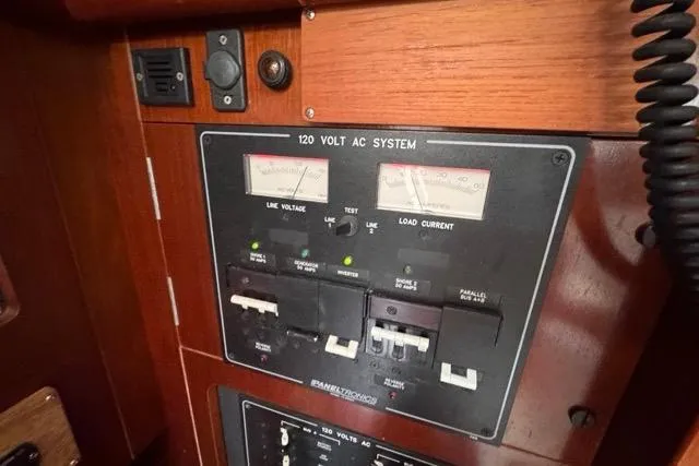 Must Love Dogs Yacht Photos Pics Electrical panel of a 1996 Beneteau 50 sailboat, featuring 120-volt AC system controls.