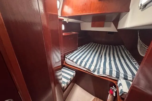 Must Love Dogs Yacht Photos Pics Cozy cabin interior of 1996 Beneteau 50 sailboat with striped bedding and wooden finish.