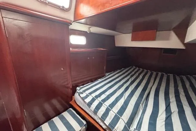Must Love Dogs Yacht Photos Pics Cabin interior of 1996 Beneteau 50 sailboat with striped bedding and wooden cabinetry.