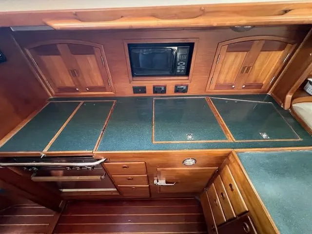 L'attitude Yacht Photos Pics 1996 Sabre 402 yacht kitchen with wood cabinetry and green countertops.