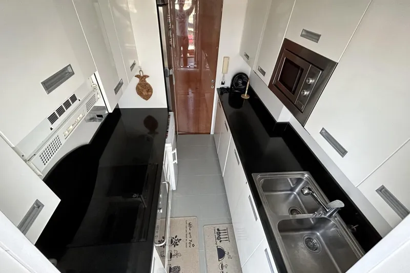  Yacht Photos Pics Modern kitchen in 2002 Sanlorenzo SL72 yacht with sleek black countertops and stainless steel sink.