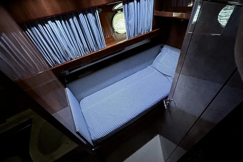  Yacht Photos Pics Cozy cabin interior of 2002 Sanlorenzo SL72 yacht with striped bedding and porthole.