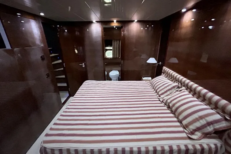  Yacht Photos Pics Luxurious Sanlorenzo SL72 2002 yacht bedroom with striped bedding and elegant wood paneling.
