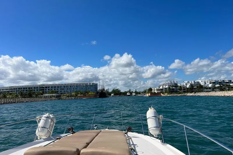2012 Sea Ray 370 Da @ Cancun Sogu Yacht Photos Pics Bow view from a 2012 Sea Ray 370 Sundancer, cruising towards a coastal cityscape under a blue sky.