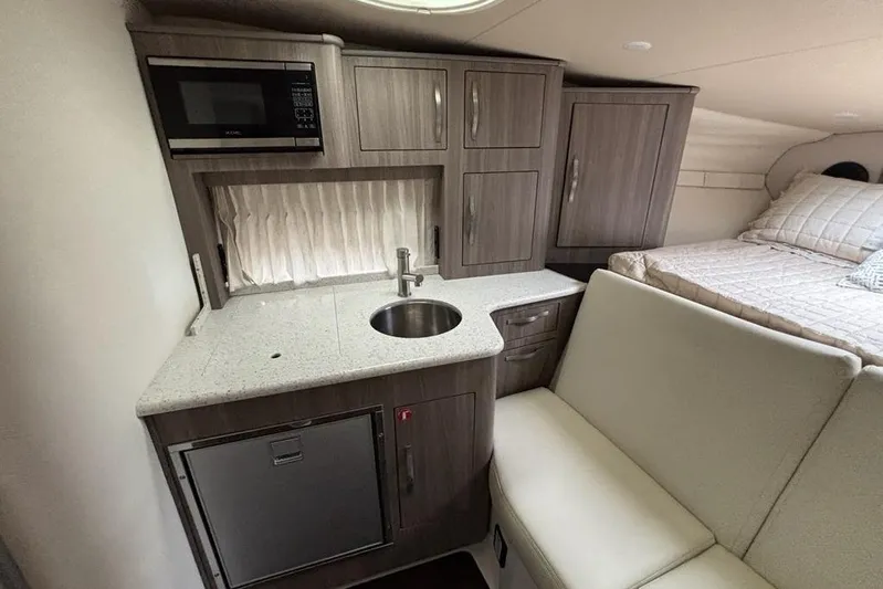  Yacht Photos Pics 2019 Regal 33 XO boat interior with kitchenette, sink, microwave, and cozy sleeping area.
