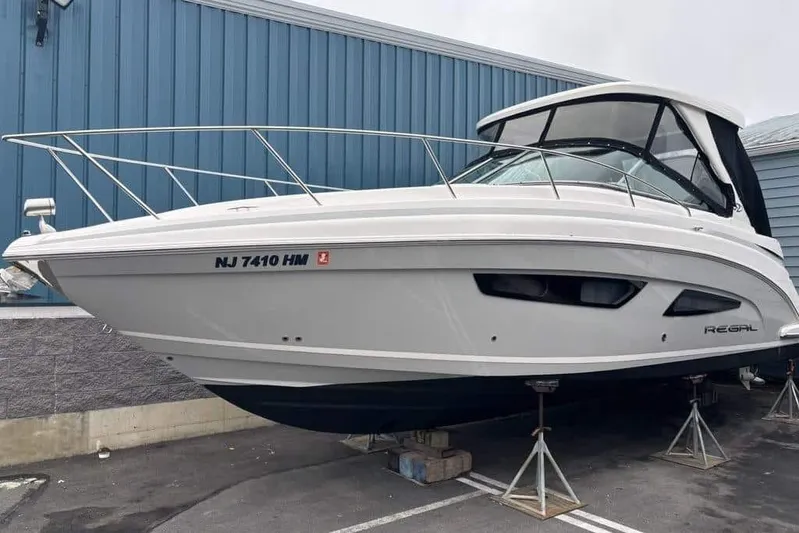  Yacht Photos Pics 2019 Regal 33 XO boat on stands, parked near a blue building.