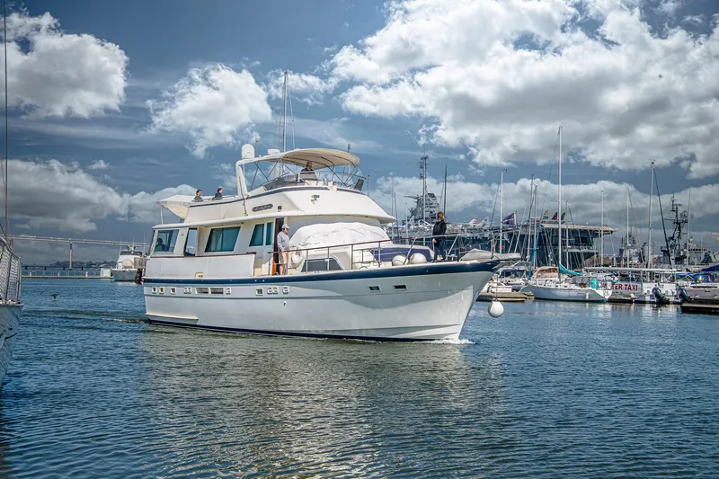 Lady Rae Yacht Photos Pics 1987 Hatteras 58 Motor Yacht cruising in a marina under a partly cloudy sky.